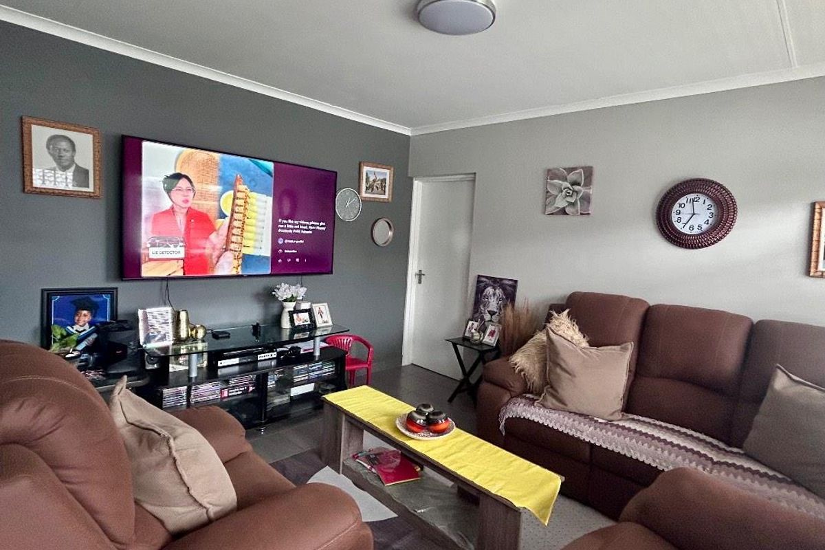 A comfortable living room featuring a dark accent wall, neutral wall tones, and a central flush mount ceiling light.