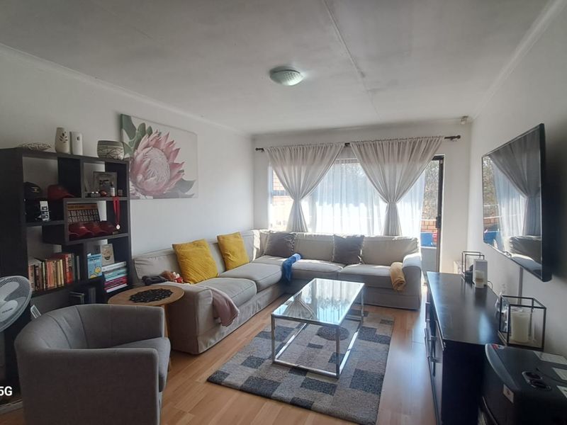 A comfortable living room featuring laminate flooring, neutral walls, and a sliding glass door providing access to the outdoor area.
