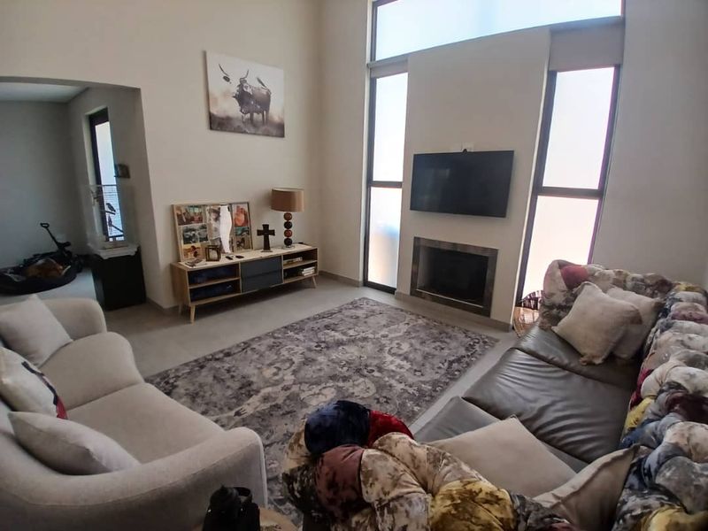Spacious living room featuring a modern fireplace, high-level windows for natural light, and neutral tiled flooring.