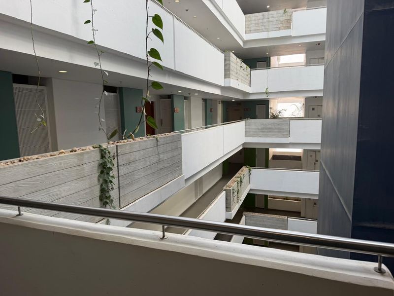 A view of the multi-level apartment building atrium featuring modern concrete planters, metal railings, and open-air corridors.