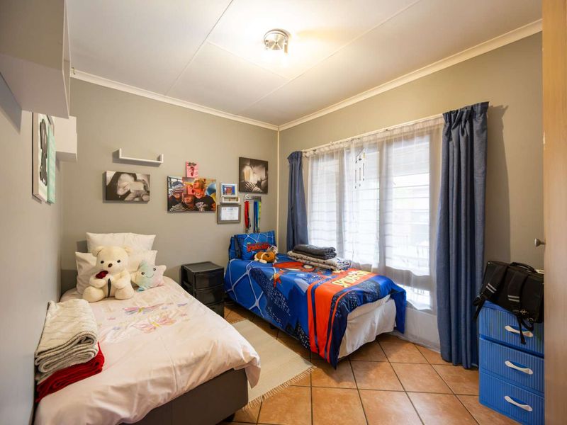 A functional bedroom featuring tiled flooring, neutral wall paint, and a sliding door providing access to the exterior.
