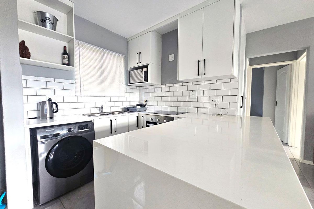 Modern kitchen featuring white cabinetry, subway tile backsplash, stone countertops, integrated oven, and a breakfast bar island.