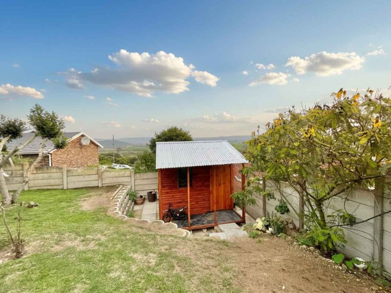 A backyard garden area featuring a timber shed with a corrugated metal roof, enclosed by precast concrete boundary walls and landscaped retaining walls.