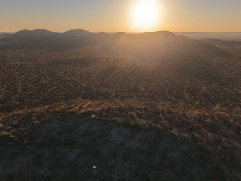 An expansive aerial view of the surrounding natural landscape and rolling hills at sunset, showcasing the property's scenic location.