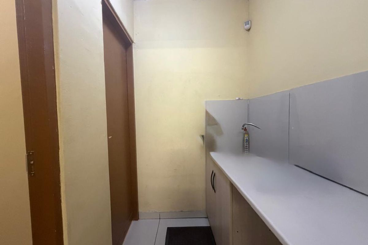 A compact utility or scullery area featuring built-in cabinetry, a countertop, and a sink faucet, suitable for prep or wash-up tasks.