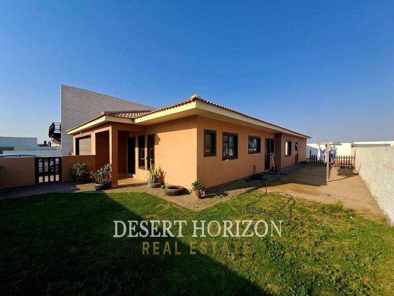Rear view of the house featuring a tiled roof, paved patio area, and a private garden with boundary walling.