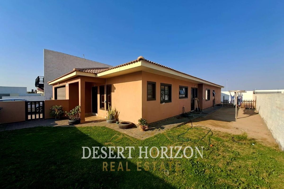 Rear view of the house featuring a tiled roof, paved patio area, and a private garden with boundary walling.