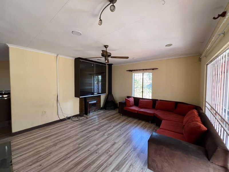 Spacious living room featuring laminate flooring, a wood-burning fireplace, and ceiling fan, with potential for cosmetic updates to enhance the interior aesthetic.
