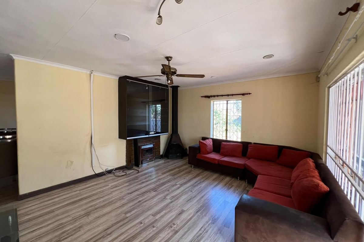 Spacious living room featuring laminate flooring, a wood-burning fireplace, and ceiling fan, with potential for cosmetic updates to enhance the interior aesthetic.