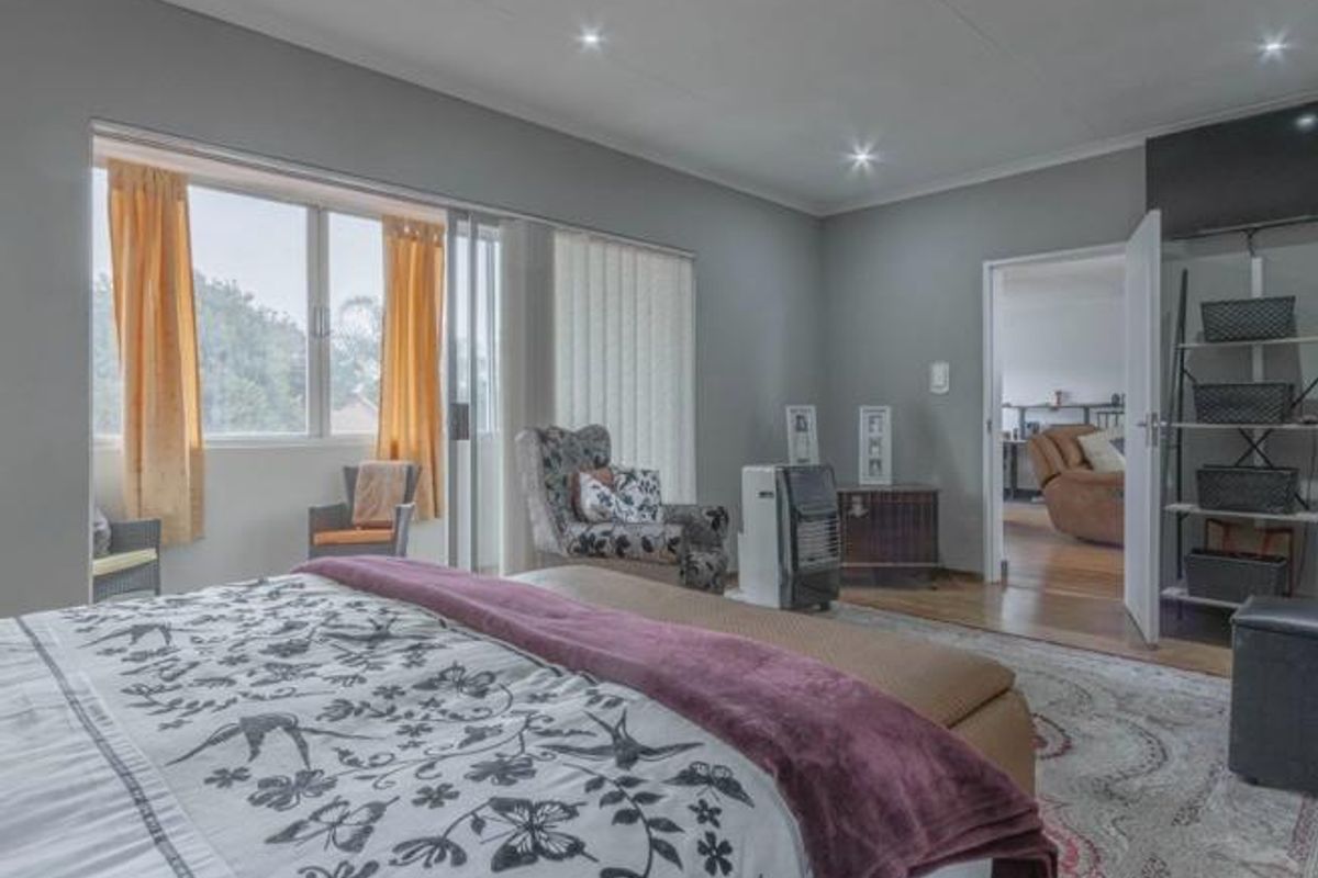 Spacious bedroom featuring large windows, recessed ceiling lighting, and direct access to an adjoining room through a doorway.