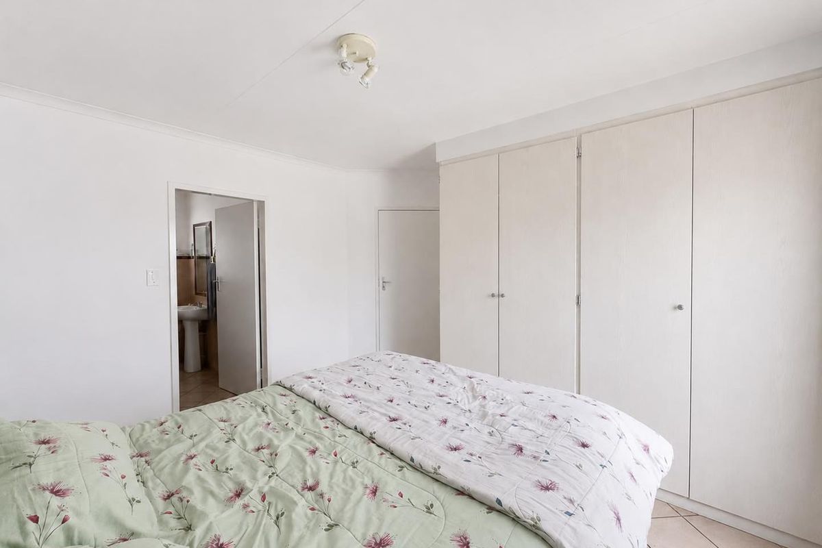 A bedroom featuring built-in cupboards, tiled flooring, and direct access to an en-suite bathroom.