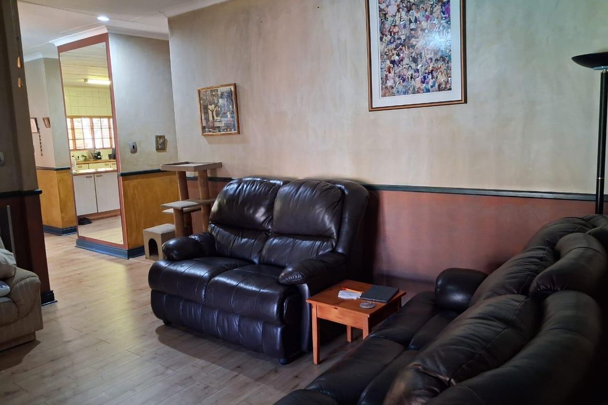 A living room featuring laminate flooring and a two-tone wall finish, with an open transition leading into the kitchen area.