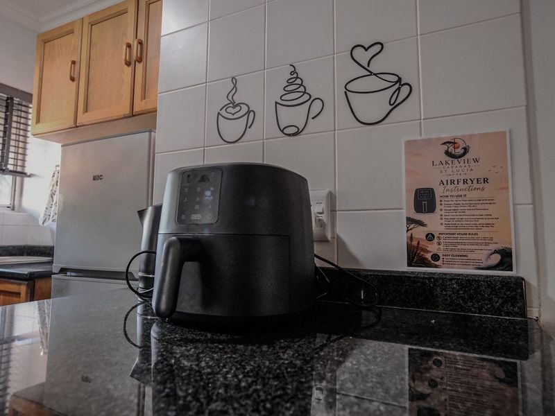 A kitchen corner featuring granite countertops, tiled backsplash with decorative wall art, and wooden cabinetry.