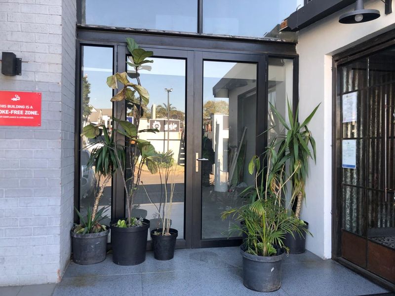 Main entrance featuring double glass doors with black metal frames, set within a painted brick facade.