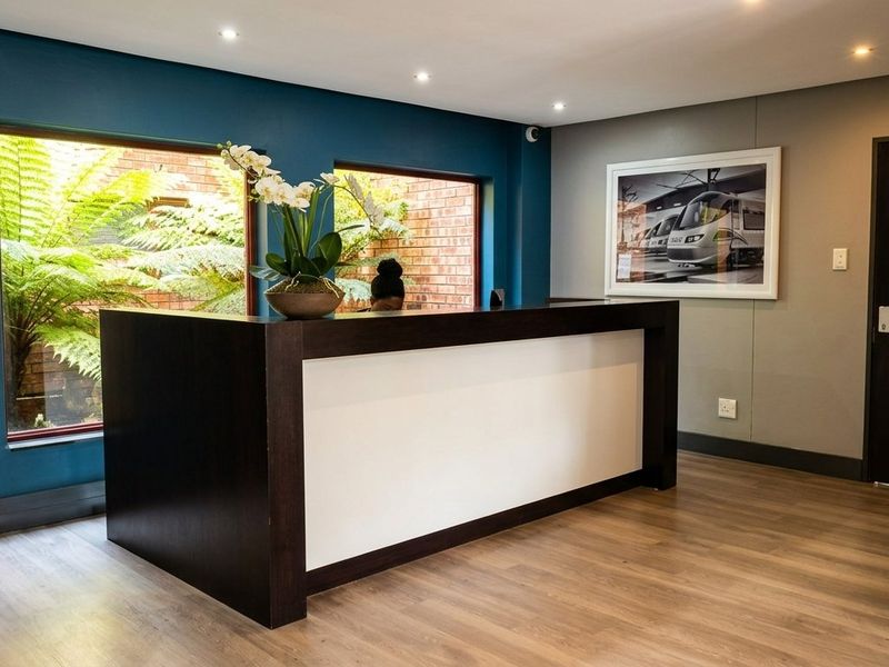 A modern reception area featuring a built-in desk, recessed lighting, laminate flooring, and a stylish exposed brick accent wall.