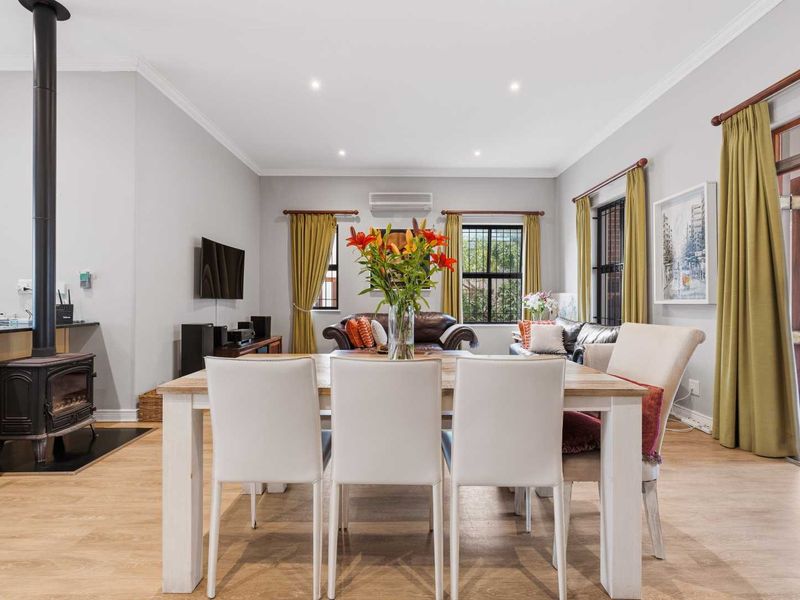 Spacious open-plan living and dining area featuring a wood-burning fireplace, recessed lighting, split-system air conditioning, and direct access to the outdoor patio.