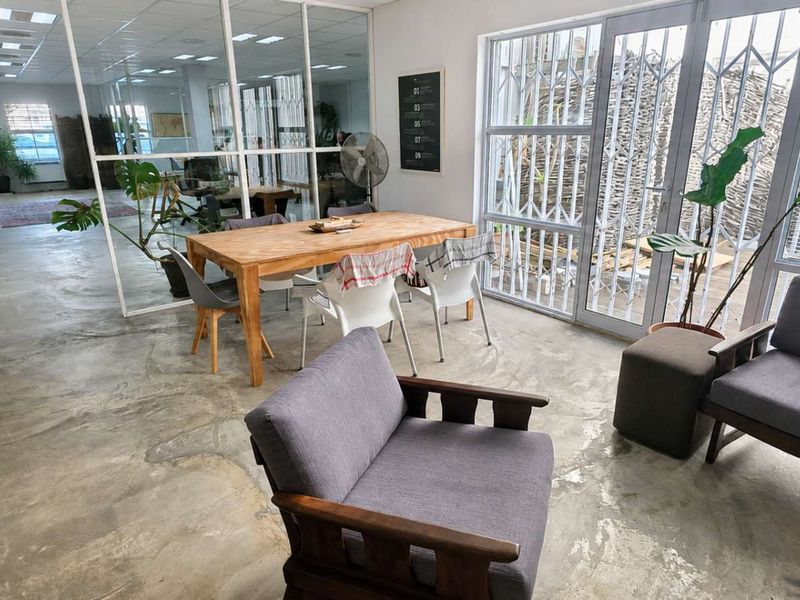 Open-plan office space featuring polished concrete flooring, glass partitioning, and large windows with security gates, providing a modern industrial aesthetic.
