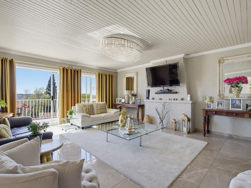 Spacious living room featuring a brick fireplace, large sliding glass doors leading to a balcony, polished tile flooring, and a decorative crystal chandelier.