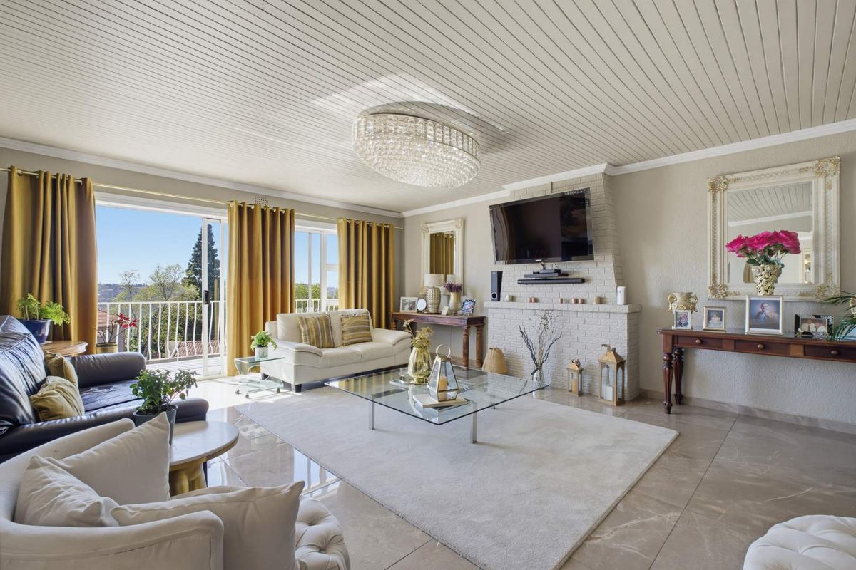 Spacious living room featuring a brick fireplace, large sliding glass doors leading to a balcony, polished tile flooring, and a decorative crystal chandelier.