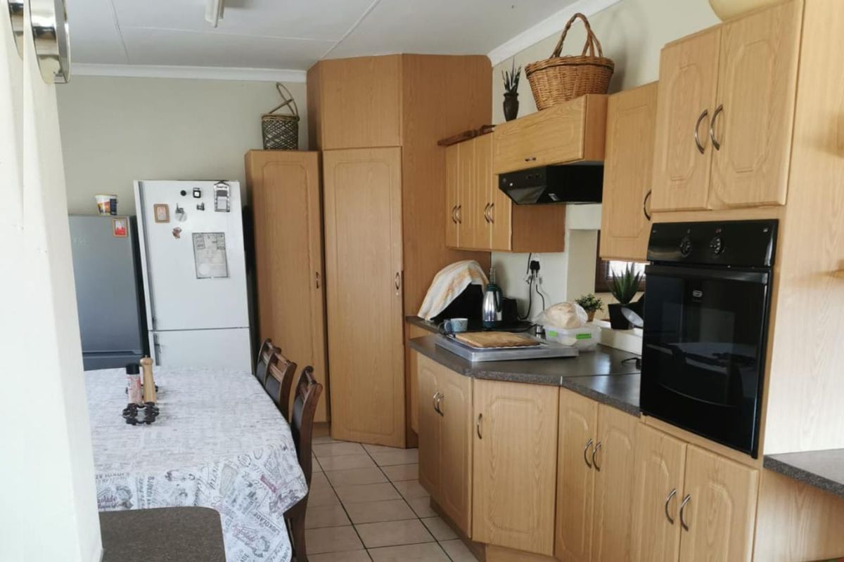A functional kitchen featuring light wood cabinetry, built-in oven, extractor fan, and tiled flooring, offering a practical layout for daily meal preparation.