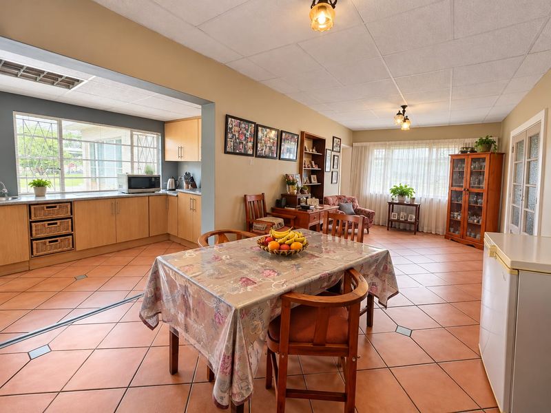 Spacious open-plan living and dining area featuring tiled flooring, integrated kitchen cabinetry, and large windows providing ample natural light.