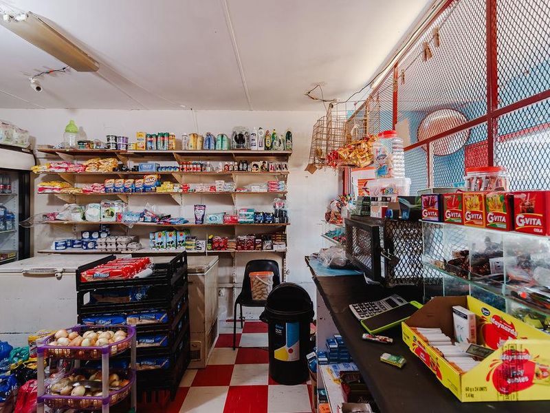 A functional retail utility space featuring built-in shelving, a service counter, and security mesh partitioning, suitable for commercial lodge operations.