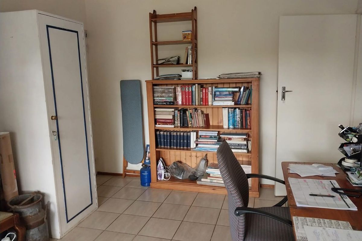 A functional room featuring tiled flooring and a built-in cupboard, suitable for use as a home office or bedroom.