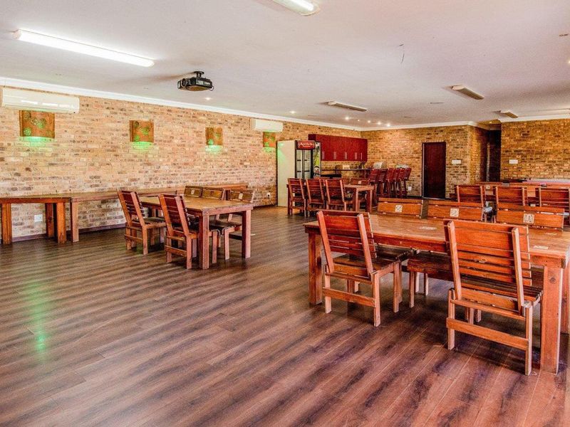 Spacious open-plan entertainment area featuring exposed brick walls, laminate flooring, multiple air conditioning units, and a built-in bar counter.