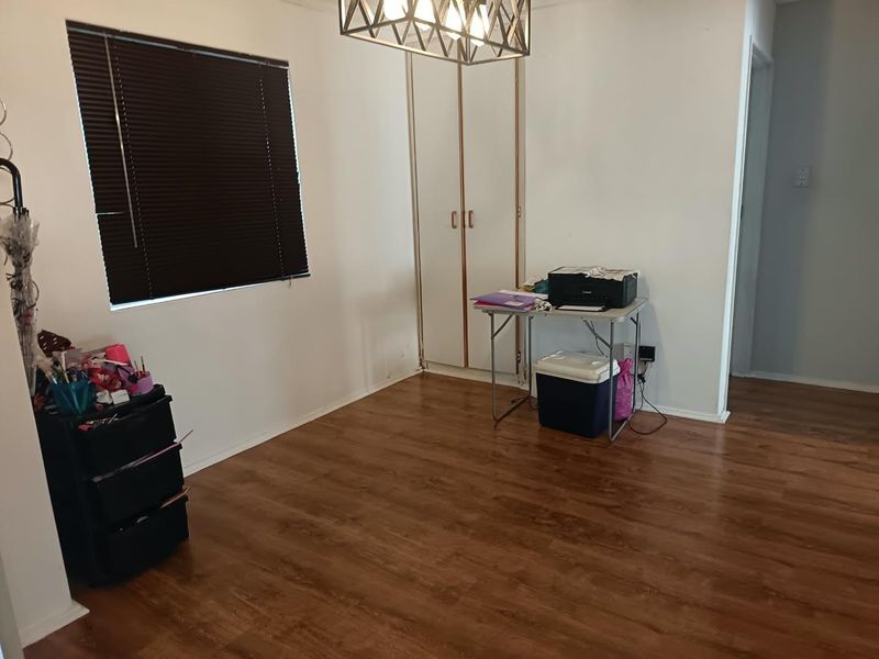 A bedroom featuring laminate flooring, a built-in wardrobe, and a modern pendant light fixture, offering a functional space with neutral finishes.