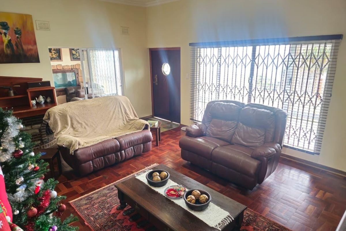 A living room featuring classic parquet flooring, a fireplace, and large sliding glass doors with security gates providing natural light.