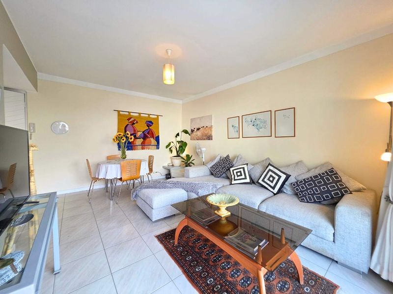 Open-plan living and dining area featuring neutral tiled flooring and classic cove cornicing, providing a versatile space for relaxation and meals.