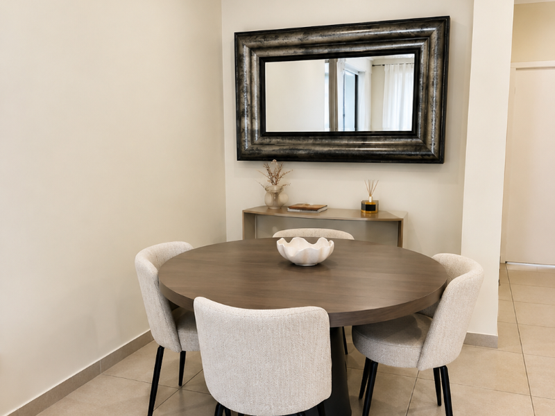 A well-maintained dining area featuring neutral tiled flooring, coved cornicing, and recessed ceiling lighting, creating a clean and functional space.