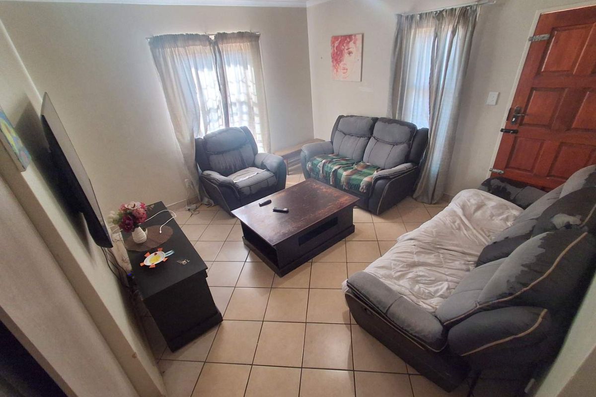 A functional living room featuring ceramic floor tiles, a timber entrance door, and coved ceiling cornices, providing a comfortable and practical living space.