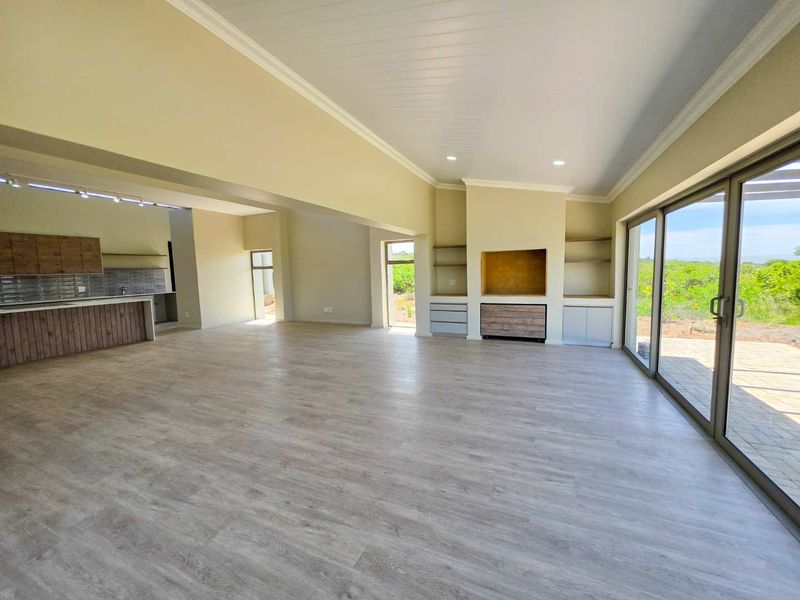 Spacious open-plan living and kitchen area featuring modern laminate flooring, built-in cabinetry, a fireplace, and large sliding doors opening to the outdoors.