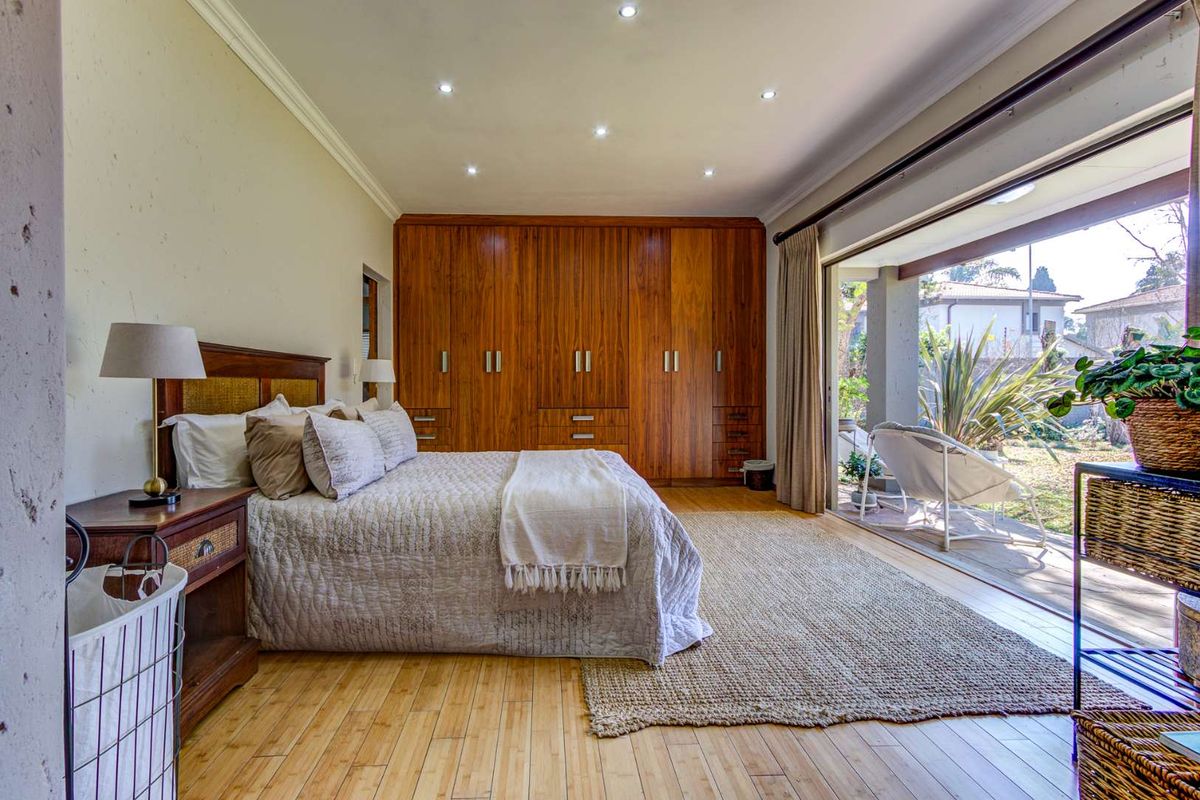 Spacious bedroom featuring extensive built-in wooden cabinetry, recessed lighting, and large sliding glass doors providing direct access to the outdoor patio area.