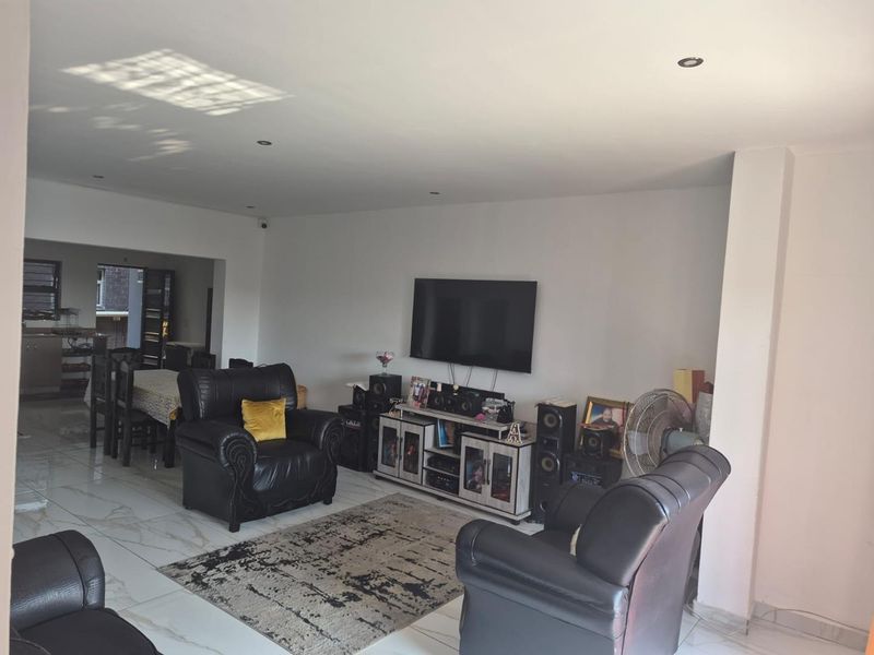 Open-plan living area featuring polished porcelain floor tiles and recessed downlighting, seamlessly connecting to the adjacent dining space.