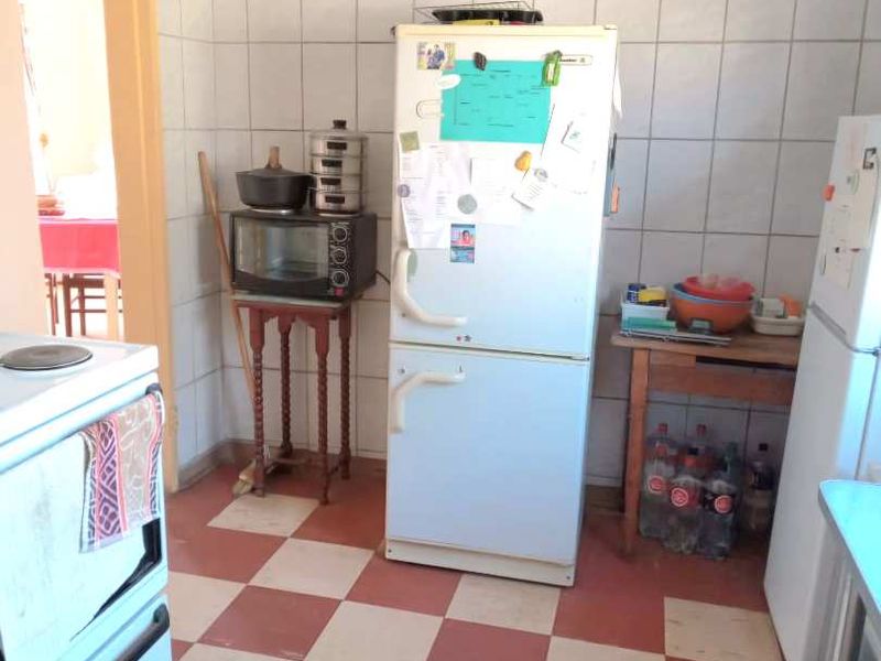 A dated kitchen area featuring checkered floor tiles and full-height wall tiling, offering a functional space with potential for modernization.
