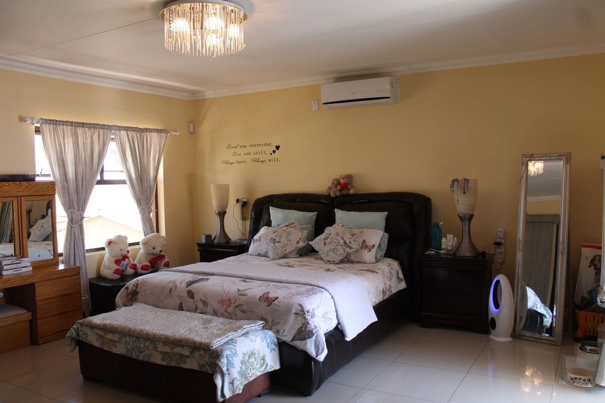Spacious bedroom featuring tiled flooring, a wall-mounted air conditioning unit, and decorative ceiling lighting.