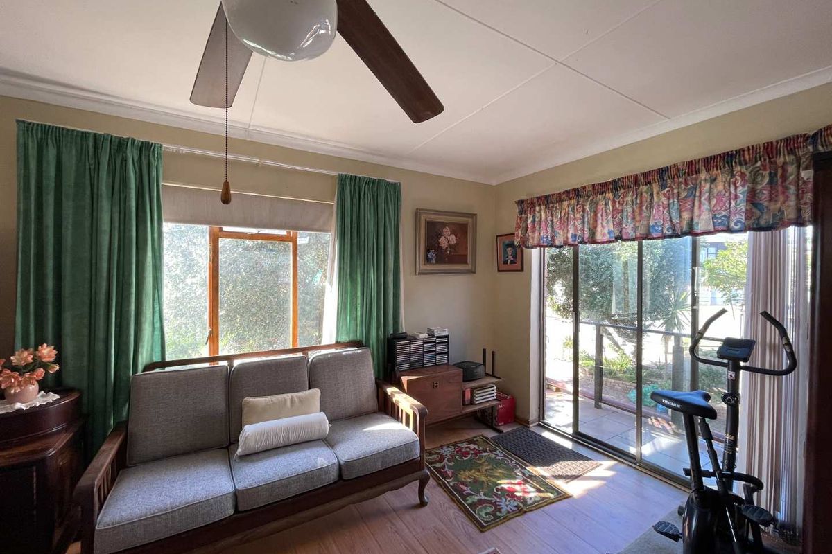 A living room featuring laminate flooring, a ceiling fan, and sliding glass doors providing access to an outdoor patio area.