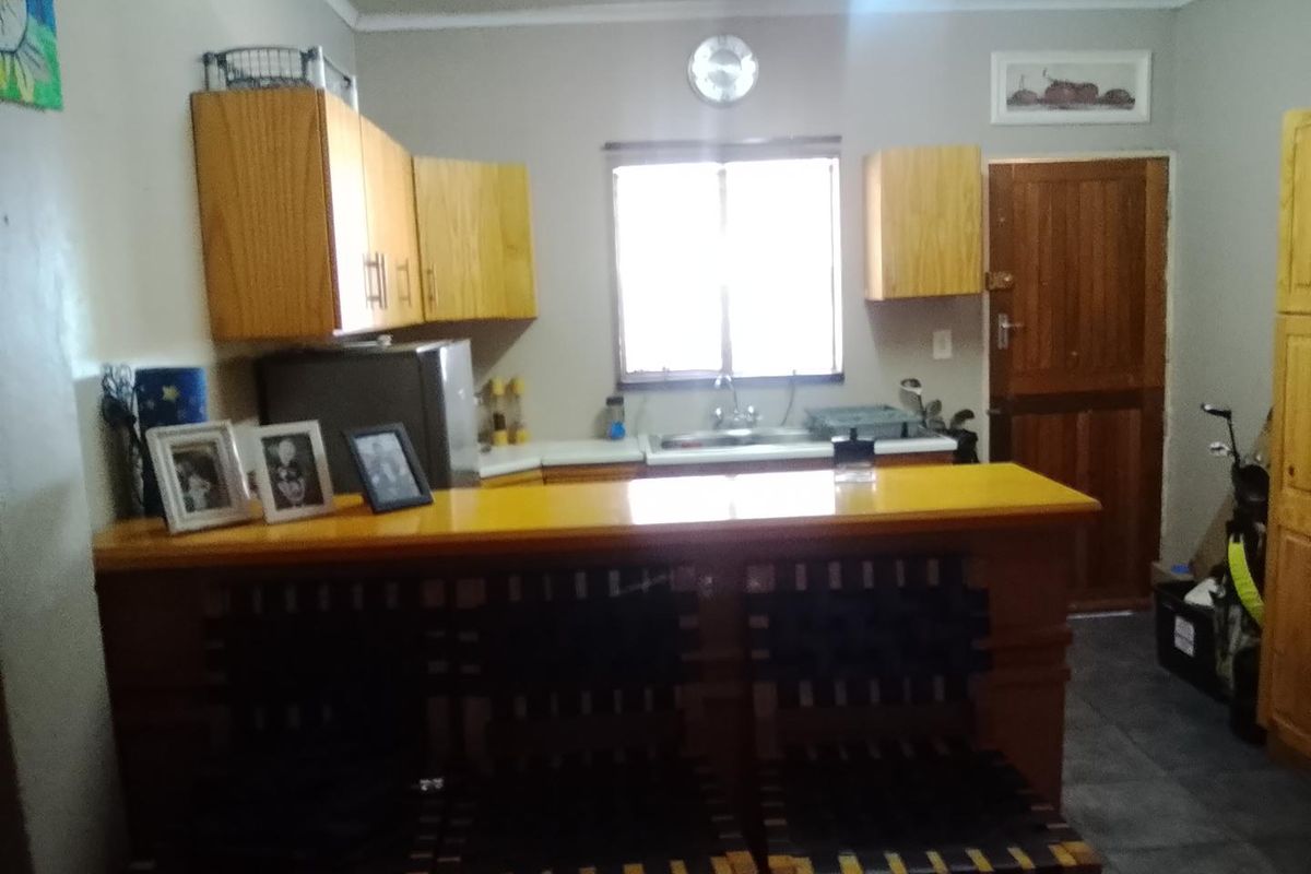 A functional kitchen featuring wooden cabinetry, a breakfast bar, and tiled flooring, providing a practical space for meal preparation and casual dining.