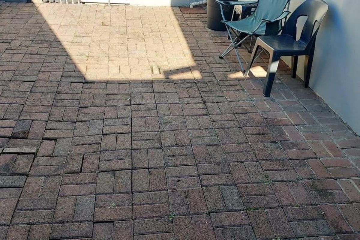 A rear courtyard area featuring brick paving that requires maintenance due to uneven and sunken sections.