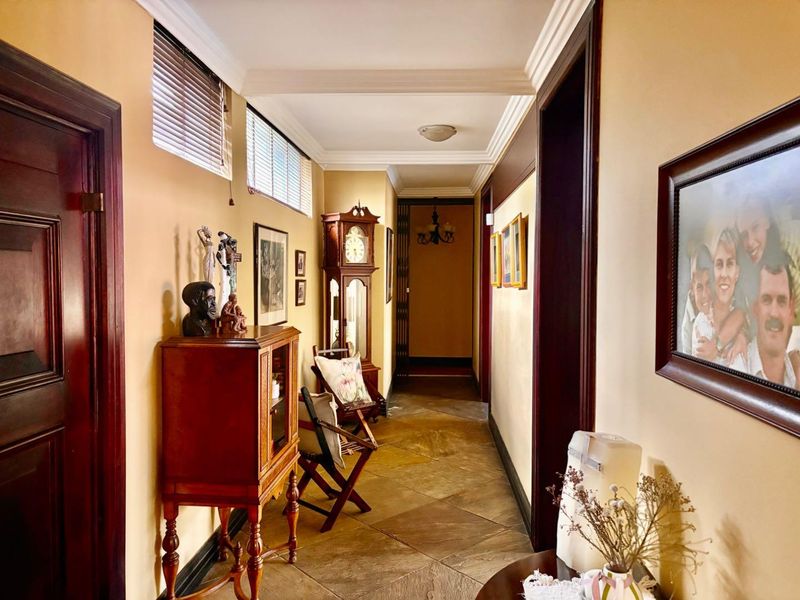 A well-maintained hallway featuring stone tile flooring, crown molding, and dark wood door frames, creating a classic and structured transition space.