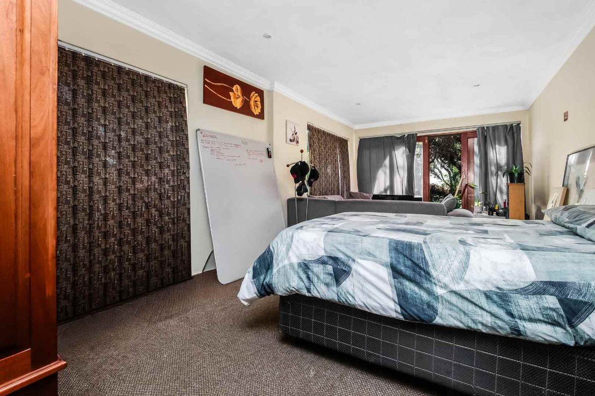 A spacious bedroom featuring neutral walls, carpeted flooring, and large sliding glass doors that provide access to the outdoor area.