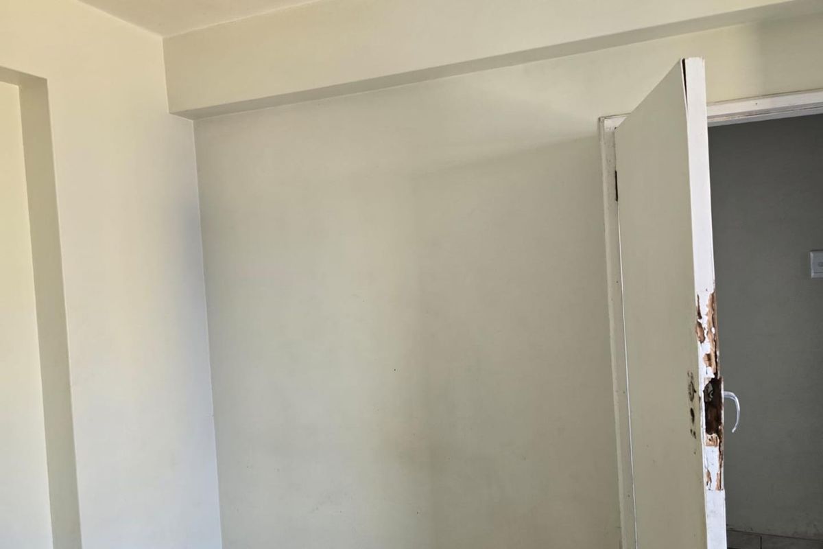 An empty bedroom featuring a damaged internal door and frame, requiring minor repairs and a fresh coat of paint.