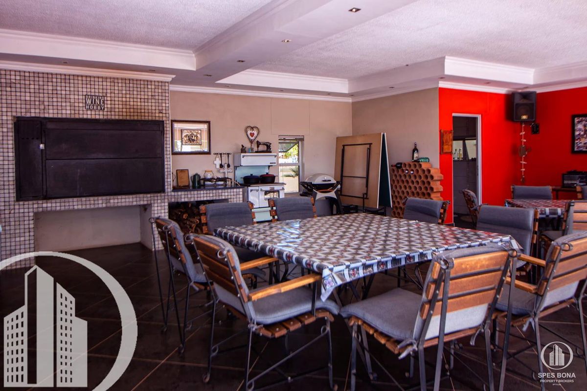 Spacious entertainment area featuring a built-in braai, tiled flooring, and recessed ceiling lighting, ideal for hosting gatherings.