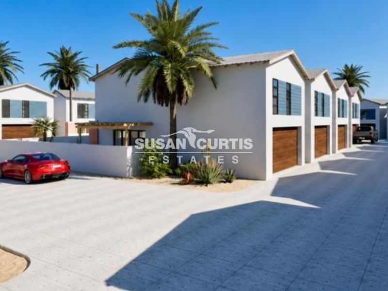 A modern townhouse complex featuring a paved driveway, multiple garage units, and clean architectural lines in a well-maintained estate setting.