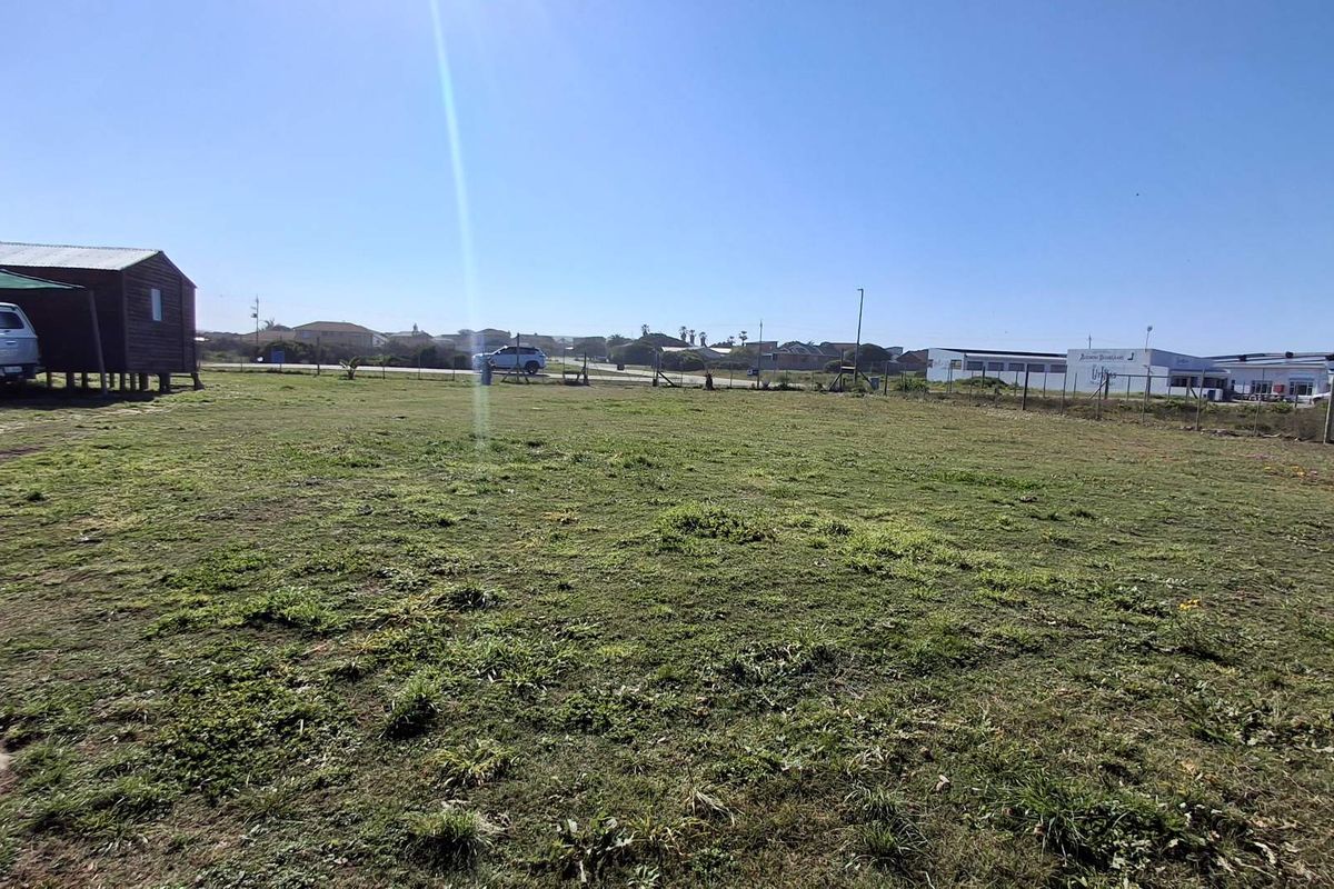 A wide, open vacant commercial land plot featuring a grass lawn and perimeter wire fencing, suitable for future development.