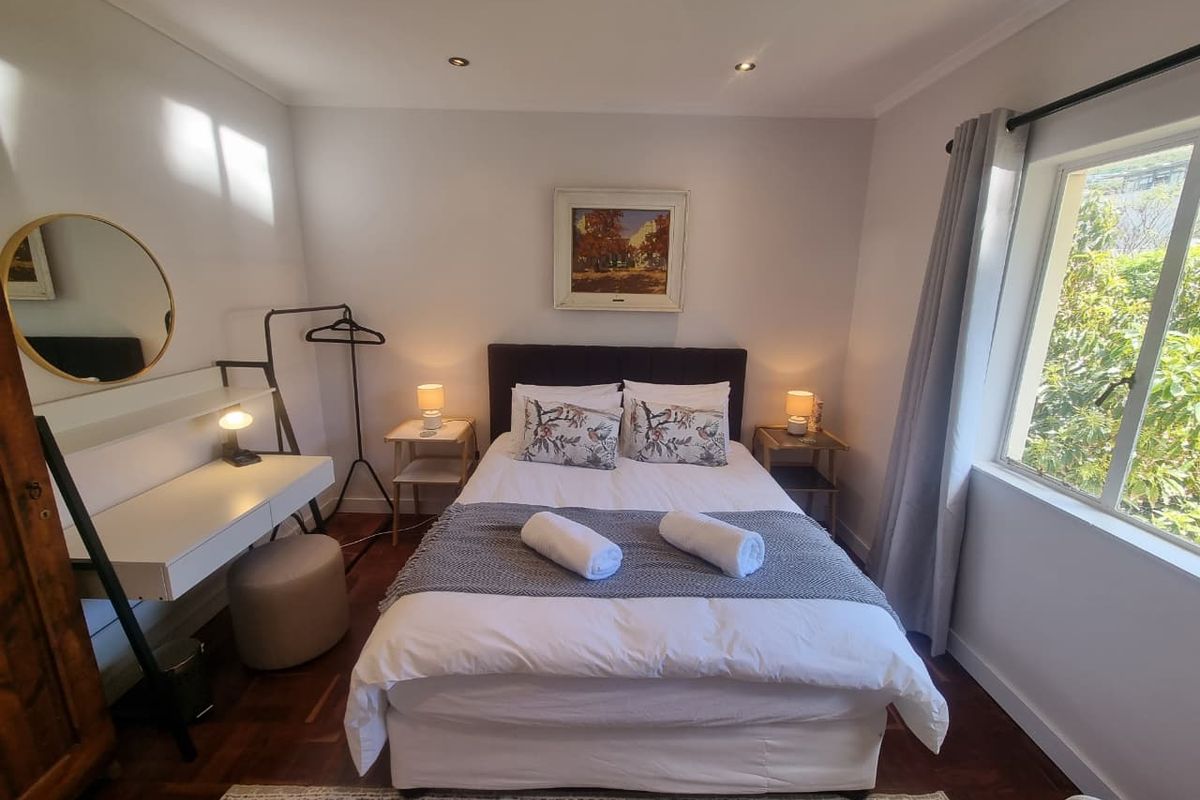 A well-maintained bedroom featuring warm parquet flooring, recessed downlighting, and a large window allowing for natural light.