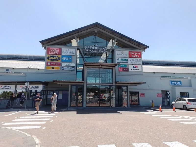 Front elevation of The Paddocks Shopping Centre featuring a prominent glass entrance, metal roofing, and integrated retail signage.