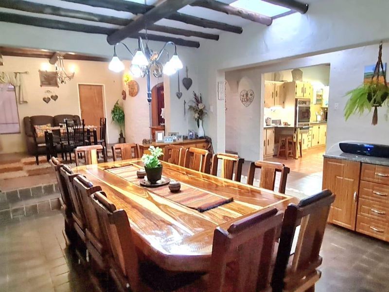 Spacious open-plan dining and kitchen area featuring rustic exposed timber ceiling beams, tiled flooring, and a skylight providing natural light.